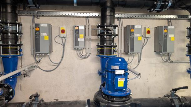 Technikraum mit neu installierter, blauer Beckenwasserpumpe und moderner MSR-Technik an der Wand, bestehend aus mehreren Steuergeräten und Leitungen.