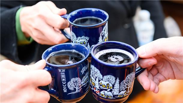 Weihnachtsmärkte in Zeiten der Energiekrise Drei Besucher stoßen in Hamburg mit Glühwein an.
