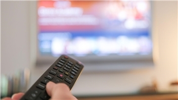 Eine Hand bedient eine Fernbedienung für ein TV-Gerät. (zu dpa: «Vodafone steckt im TV-Geschäft im Abwärtssog»)