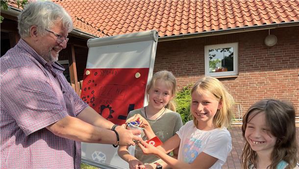 Mann nimmt von Schülerinnen Geldspende entgegen