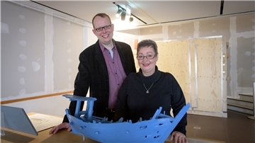 DSM-Sprecher Thomas Joppig und Bau-Sachbearbeiterin Claudia Brenneis haben eine Mini-Kogge vor sich. In den Kiste hinter ihnen warten - gut verpackt - die hölzernen Galionsfiguren „Elisabeth“ und „Hertha“ auf das Ende der Bauarbeiten.