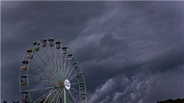 Dunkle Regenwolken ziehen über ein Riesenrad auf dem Gelände des Hurricane-Festivals in Scheeßel hinweg.