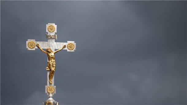 Dunkle Wolken über einem Kruzifix: Immer mehr Menschen nehmen Abstand von der Katholischen Kirche.