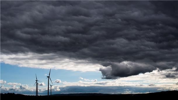 Dunkle Wolken ziehen über Windräder hinweg. Sturm droht, das heißt viel wind, aber deswegen nicht unbedingt mehr Strom.