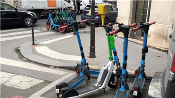 E-Scooter von drei verschiedenen Anbietern stehen auf dafür vorgesehenen Parkplätzen.