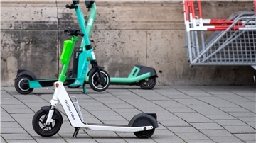 E-Scooter von Lime, Tier und Bolt stehen in Berlin auf einem Gehweg.