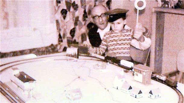 In dieser Mini-Welt ist jedes Detail ein Unikat Ein altes Foto. Ein älterer Mann hat einen Jungen auf dem Schoß. Im Vordergrund eine Modelleisenbahn.