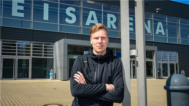 Ein Fitnesstrainer steht vor der Eisarena.