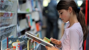 Junge Leserin stöbert in einem Bücherbus