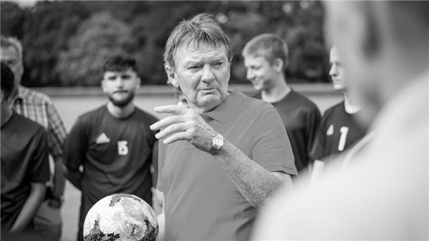 Fußballtrainer Egon Coordes umringt von Spielern.