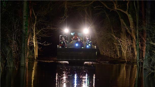 Hochwasser hält Niedersachsen und Bremen in Atem Ehrenamtliche Einsatzkräfte der Feuerwehr werden unweit der Aller mit einem Radlader über eine überflutete Straße gefahren.