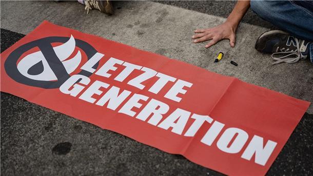 Letzte-Generation-Razzia: Forscher warnt vor Radikalisierung Ein Aktivist der Gruppe „Letzte Generation“, der seine Hand selbst auf der Straße festgeklebt hat, blockiert eine Kreuzung in Göttingen.