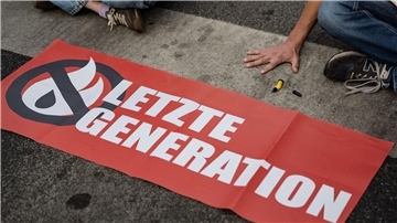 Ein Aktivist der Gruppe Letzte Generation hat seine Hand auf der Straße festgeklebt und blockiert eine Kreuzung.