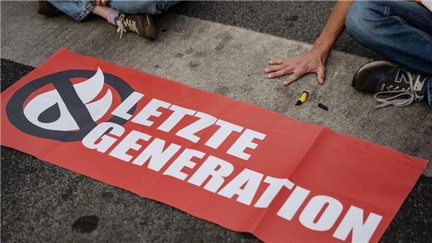 Aktivist angefahren: Gericht prüft Führerscheinentzug Ein Aktivist der Gruppe Letzte Generation hat sich auf eine Straße festgeklebt und blockiert eine Kreuzung. (Symbolbild)
