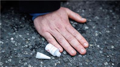 Ein Aktivist der Klimaschutz-Initiative „Letzte Generation“ ist mit der Hand auf die Straße geklebt.