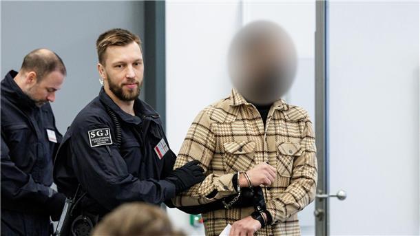 Ein Angeklagter (r) wird von Justizbeamten in Handschellen in den Gerichtssaal des Oberlandesgerichts Dresden geführt.
