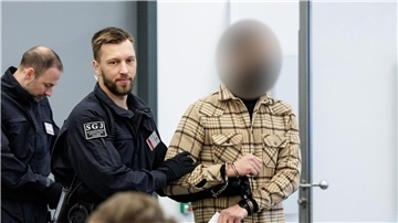 Ein Angeklagter (r) wird von Justizbeamten in Handschellen in den Gerichtssaal des Oberlandesgerichts Dresden geführt.