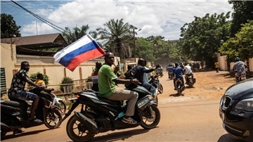 Ein Anhänger von Hauptmann Traore schwenkt eine russische Fahne auf einem Motorrad.