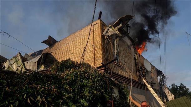 Ein Anwohner löscht ein Feuer in einem Haus, das nach russischem Beschuss in Cherson, Ukraine, beschädigt wurde.