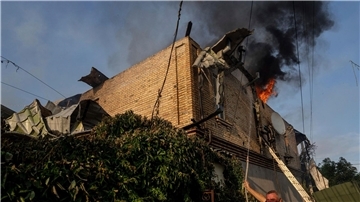 Ein Anwohner löscht ein Feuer in einem Haus, das nach russischem Beschuss in Cherson, Ukraine, beschädigt wurde.