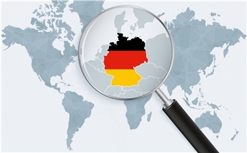 Eine Weltkarte in Grau. Eine Lupe rückt Deutschland in den Fokus. 