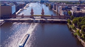 Ein Ausflugsschiff fährt unweit der Oberbaumbrücke auf der Spree in Richtung Innenstadt.