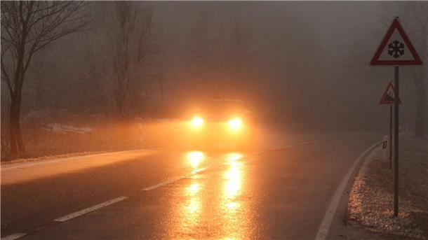 Verkehrsunfälle wegen Schnee und Glätte in Niedersachsen Ein Auto fährt bei Glatteis und Nebel über eine Straße.