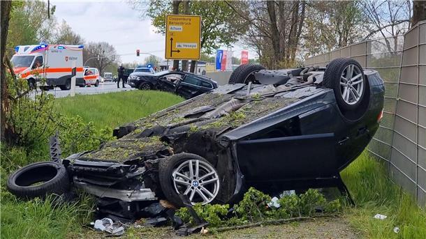 Ein Auto liegt nach einem Unfall auf dem Dach, während Rettungskräfte im EInsatz sind.