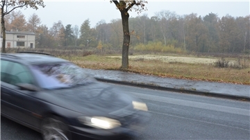 Ein Auto passiert das seit Jahren umstrittene Grundstück an der Bremer Landstraße in Tarmstedt. Dort befand sich einst ein Kalksandsteinwerk, Reste der Betriebsgebäude sind links im Hintergrund auf einem benachbarten Grundstück zu erkennen.