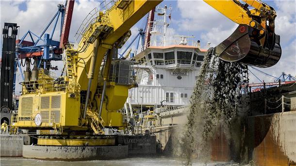 Ein Bagger baggert Schlick aus der Elbe.
