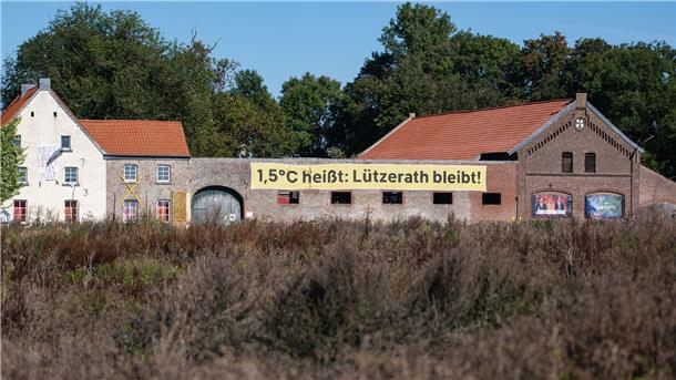 Ein Banner mit der Aufschrift „1,5 Grad heißt: Lützerath bleibt!“ an einem alten Hof in Lützerath. Doch nun soll das Dorf weichen.