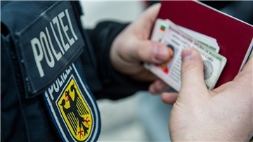 Ein Beamter der Bundespolizei hält bei einer Kontrolle ausländische Ausweise in den Händen.