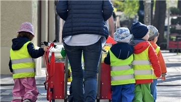 Ein Betreuerin läuft mit mehreren Kleinkindern durch München.
