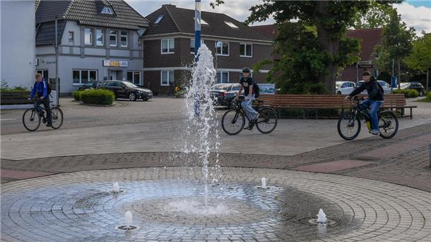 Drei junge Menschen fahren mit dem Fahrrad über einen Marktplatz.