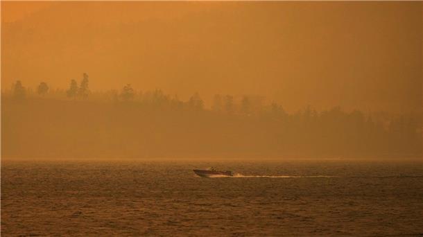 Menschenleere Städte: Kanada kämpft gegen Feuer Ein Boot fährt auf dem Okanagan-See, während der Rauch des McDougall-Creek-Wildfeuers über dem Gebiet liegt.