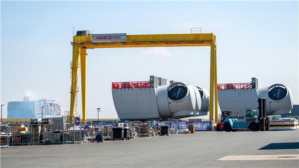 Unterstützung für Hafenausbau durch Bund weiter unklar Ein Containerschiff fährt an den Offshore-Maschinenhäusern auf dem Werkgelände von Siemens Gamesa in Cuxhaven vorbei.