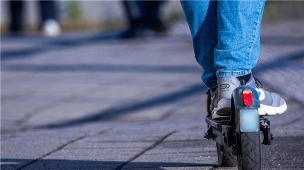 Ein Reisender fährt mit seinem E-Scooter über einen Bahnsteig.
