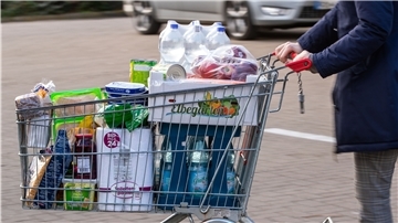 Ein Einkaufswagen mit Lebensmitteln und Produkten des täglichen Bedarfs wird über den Parkplatz eines Supermarkts geschoben - auch dort gilt die Maskenpflicht. 