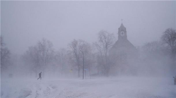 Wintersturm „Elliott“: Weihnachten unter Extrembedingungen Ein einsamer Fußgänger in Schneeschuhen geht über den Colonial Circle, während sich die St. John’s Grace Episcopal Church in Buffalo inmitten eines Schneesturms aus dem Schneetreiben erhebt.