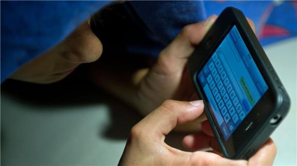 Wie Kinder weniger Zeit vor Bildschirmen verbringen Ein elfjähriger Junge liegt unter der Bettdecke und schreibt auf einem Smartphone eine SMS. Kinder unter 13 Jahren sollten Experten zufolge keinen Zugang zu derartigen Medien haben.