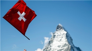 Ein Fahnenwerfer mit der Schweizer Flagge in Aktion vor der Kulisse des Matterhorns.