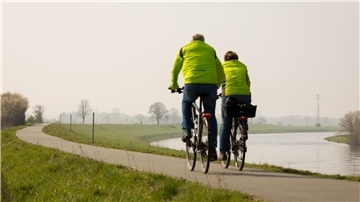 Ein Fahrradfahrer und eine Fahrradfahrerin sind auf dem Weser-Radweg unterwegs. Wer eine solche Tour plant, kann sich in einem neuen Wanderführer für das 2025 informieren.