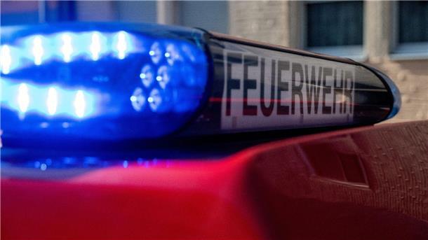 Ein Fahrzeug der Feuerwehr steht mit eingeschaltetem Blaulicht an einem Einsatzort.