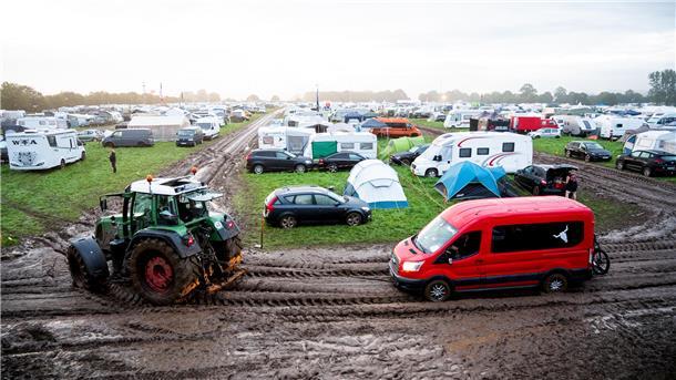 Ein Fahrzeug wird mit Hilfe eines Traktors auf das Gelände des Heavy-Metal-Festivals in Wacken durch den Schlamm gezogen. Das WOA gilt als größtes Heavy-Metal-Festival der Welt.
