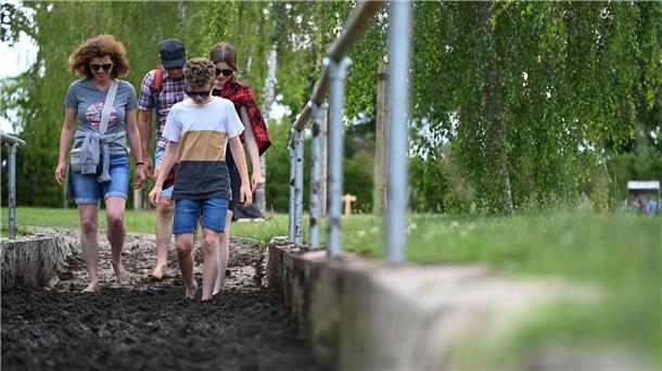 Ein Familie geht im Barfußpark durch die Moorstrecke.