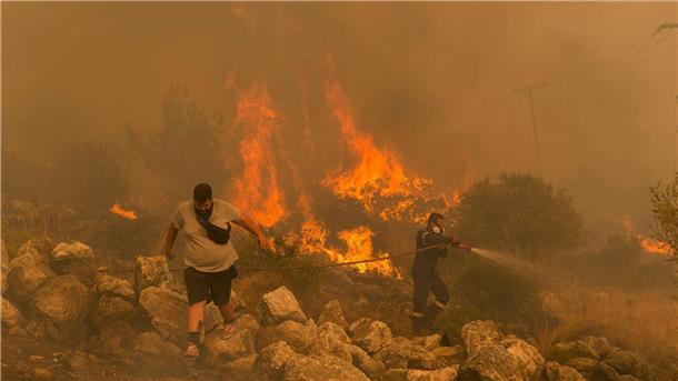 Das Jahr der Klimarekorde: Extrem ist das neue Normal Ein Feuerwehrmann kämpft am im Dorf Hasia in der Nähe von Athen gegen einen Waldbrand.