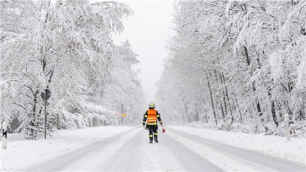 Ein Feuerwehrmann sperrt die Landstraße in Richtung Großer Feldberg (Taunus).