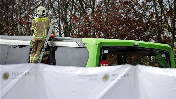 Busunfall auf A9: Polizei korrigiert Zahl der Toten auf vier Ein Feuerwehrmann untersucht den Reisebus hinter mobilen Sichtschutzwänden.