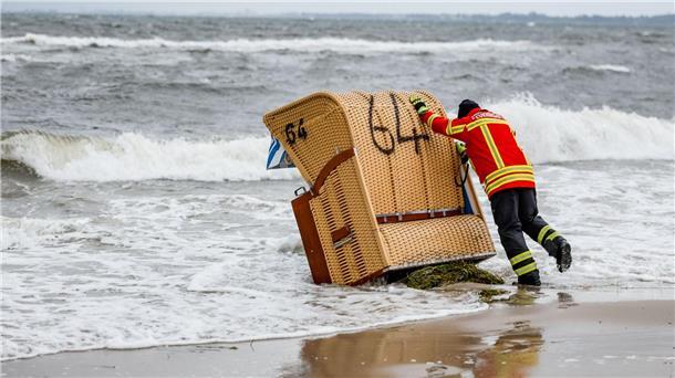 Schwere Sturmflut setzt der Ostsee-Küste zu - Eine Tote Ein Feuerwehrmann versucht, in Kiel-Schilksee einen Strandkorb vor den Flutwellen der Ostsee zu sichern.