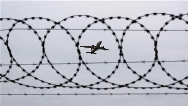 Mehr Menschen aus Niedersachsen und Bremen abgeschoben Ein Flugzeug startet am Flughafen Hannover - fotografiert durch Stacheldraht am Flughafenzaun.